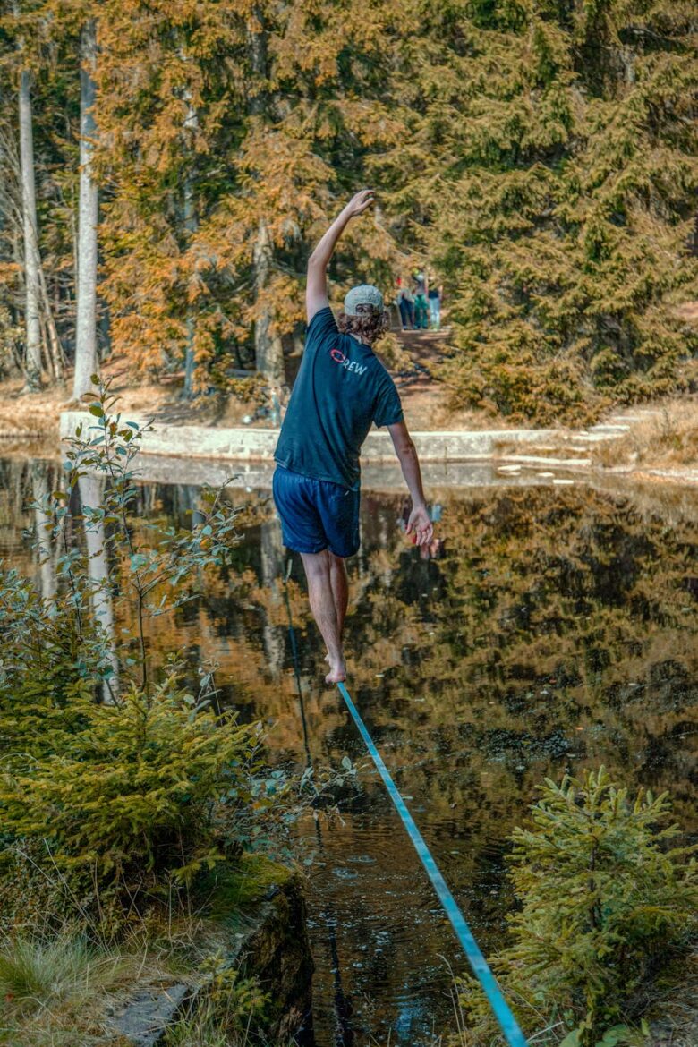 man walking on a rope over a lake